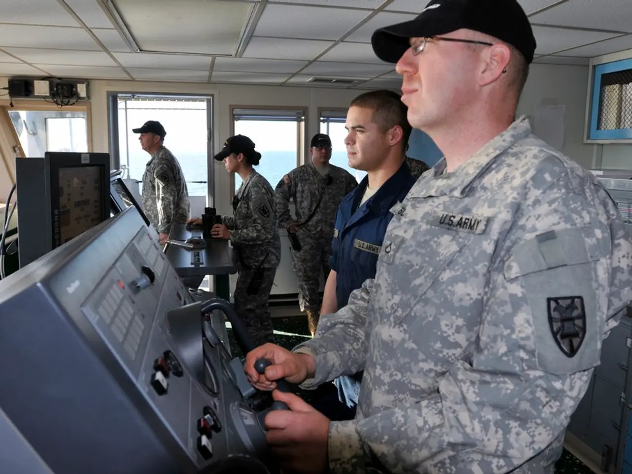 In this image there are people standing in a room, two people are operating machines, in the...