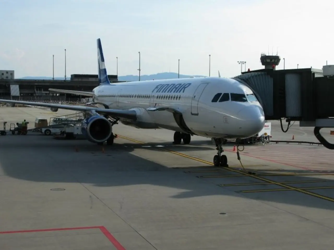 In the image there is an aeroplane on the runway, in the back there are buildings and above its...