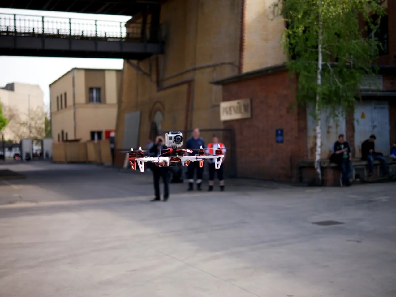 In this image there is a quadcopter in the foreground. There is a road at the bottom. There are...