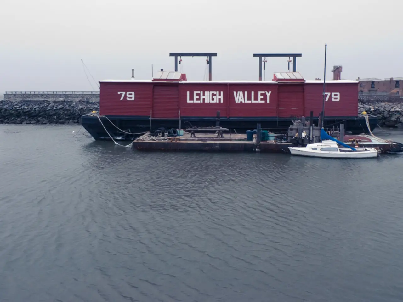 The picture is taken on the shore. In the foreground there is a water body. In the center of the...