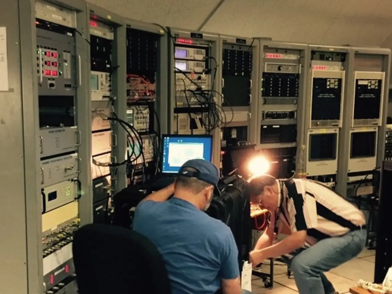 This picture shows a generator room where two people working on a laptop