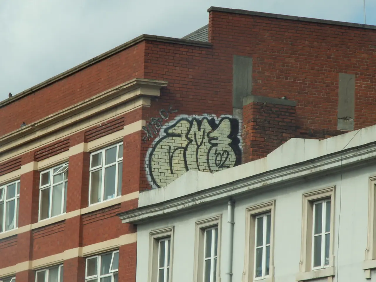 In this image in the front there are buildings and the sky is cloudy.