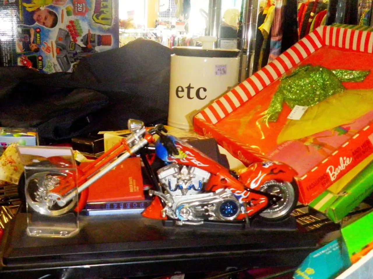 In this image we can see a toy motor bike, some toys, a memento, some cardboard boxes and...