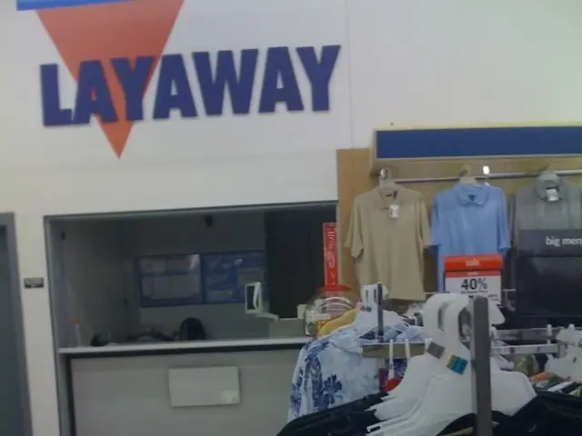 This picture shows an inner view of a store and we see clothes to the hangers and we see e table...