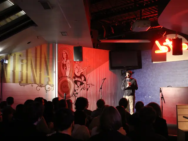 A man is standing near the microphone, here people are standing, here there is television and...