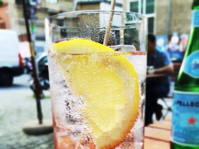 In this image we can see glass and some liquid in it, and here is the lemon and here is the bottle...