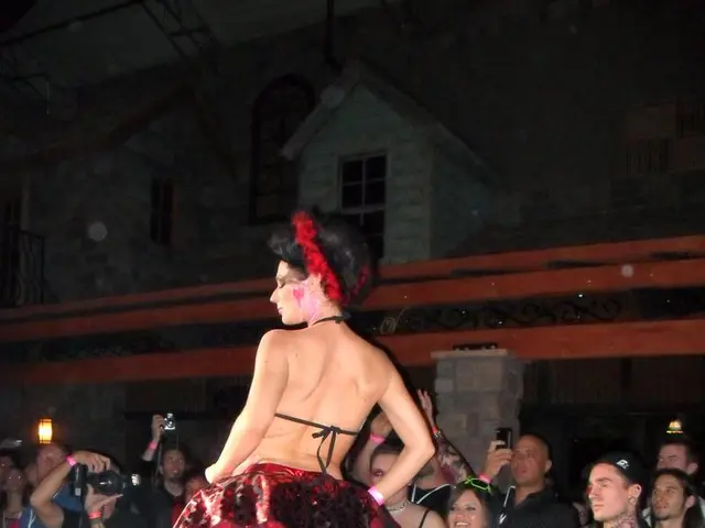 In this image we can see a person wearing red color dress standing on the surface which is of black...