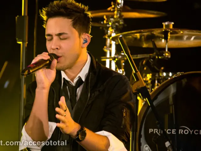 In the image we can see there is a person who is holding a mike in his hand and at the back there...