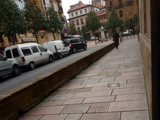 In this image, we can see few vehicles are parked on the road. Here a person is on the walkway....