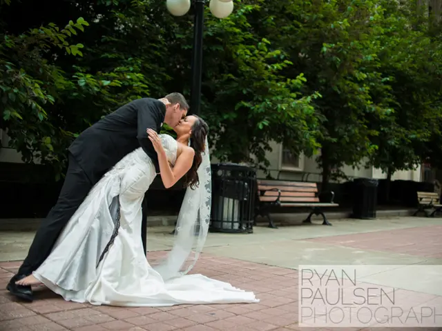 In the image there is a bride and a bridegroom kissing each other. In the background there are...