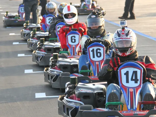 In this image I can see people sitting on go-karts. These people are wearing helmets. These...
