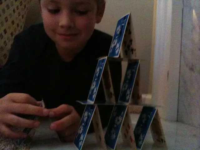 In the image I can see a kid wearing black color T-shirt playing with cards which are in blue color...