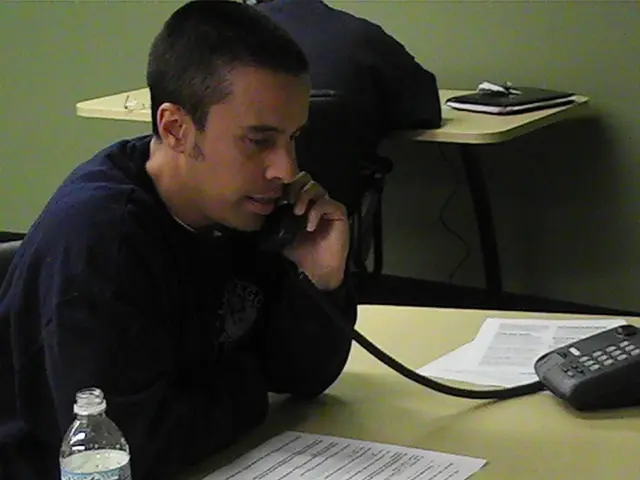 In this image we can see persons sitting on the chairs and one of them is talking to the telephone...