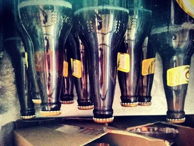 In this image there are bottles. At the bottom there are cardboard boxes.