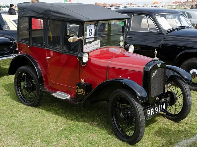 In this image there is a red color jeep on the ground. Behind it there are few other cars which are...