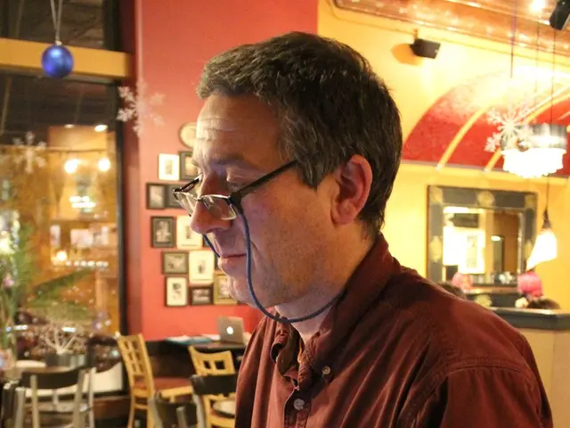 This picture shows a man seated and working on a laptop in a store