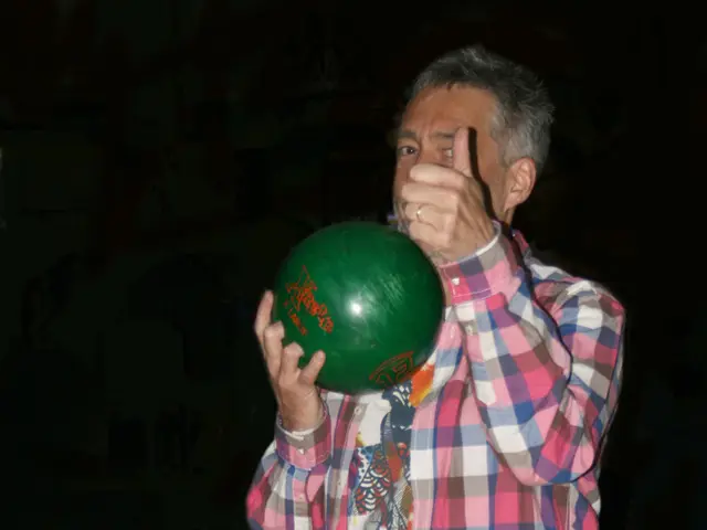 In this image we can see a man standing holding a ball. We can also see a group of balls which are...