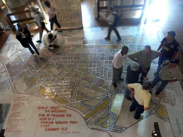 In this image we can see people standing on the polythene sheet and one of them is sitting. In the...