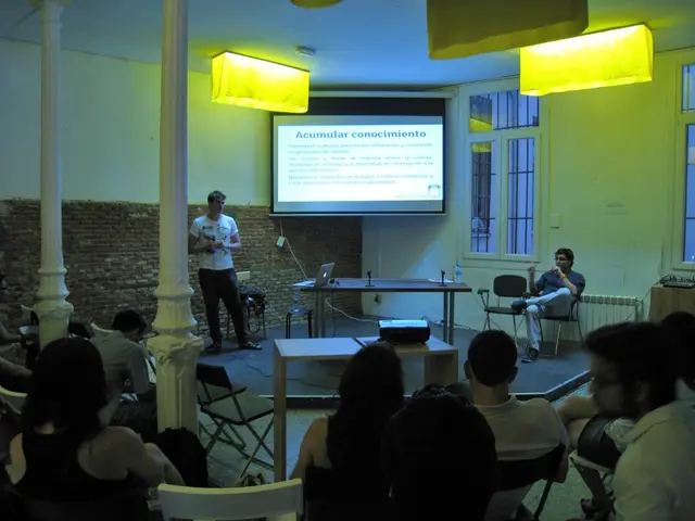 This image is clicked in a room. It looks like a meeting room. There are many persons sitting in...