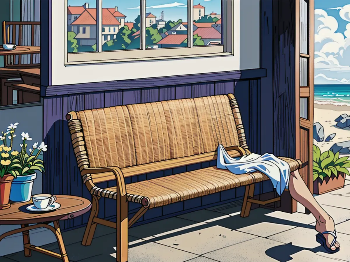 Outdoor seating arrangement featuring a wicker bench, accompanying side table, straw handbag, and sandals situated before a blue dwelling that overlooks a sandy shoreline and the ocean.